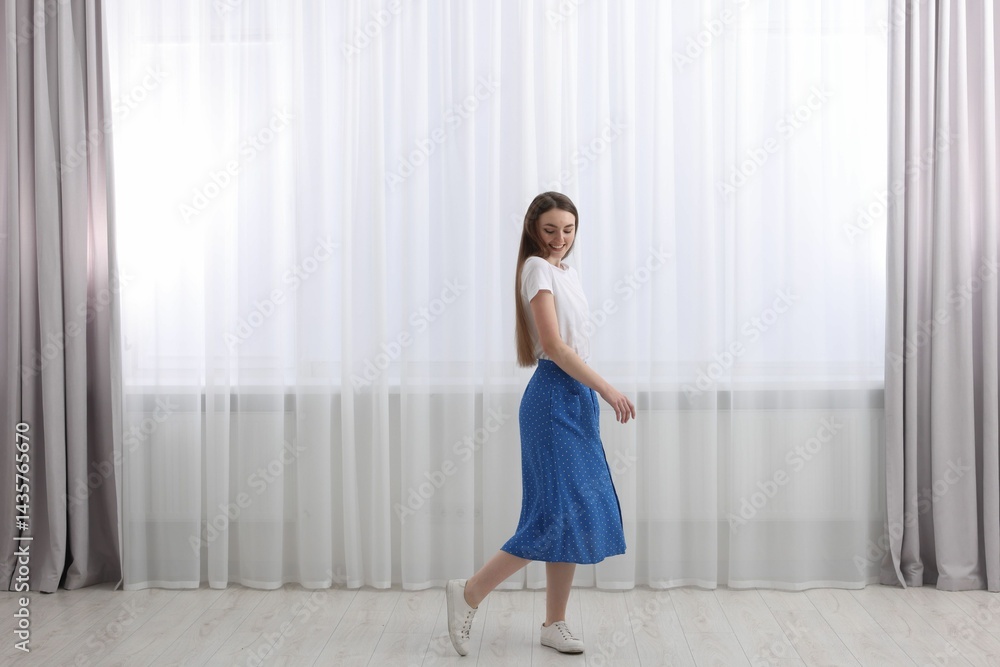 Woman standing near window with stylish curtains at home. Space for text Woman standing near window with stylish curtains at home. Space for text