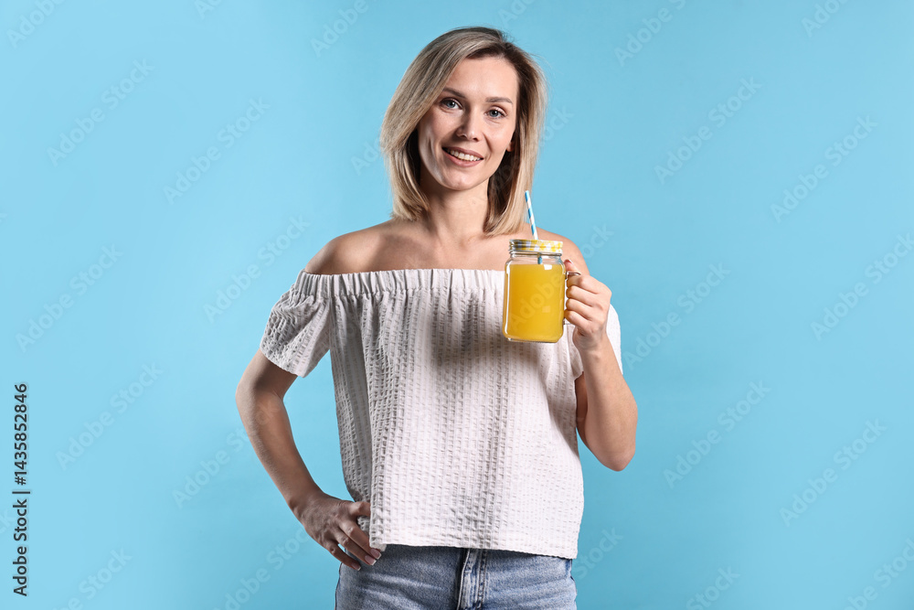 Woman with mason jar of orange juice on light blue background. Refreshing drink Woman with mason jar of orange juice on light blue background. Refreshing drink