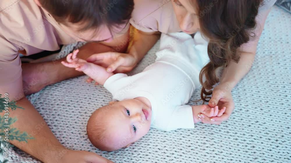 Parents interact with their baby on a soft blanket in a warmly lit room. The atmosphere is filled with joy as they engage in gentle play, making the child smile and explore their surroundings. The Parents interact with their baby on a soft blanket in a warmly lit room. The atmosphere is filled with joy as they engage in gentle play, making the child smile and explore their surroundings. The