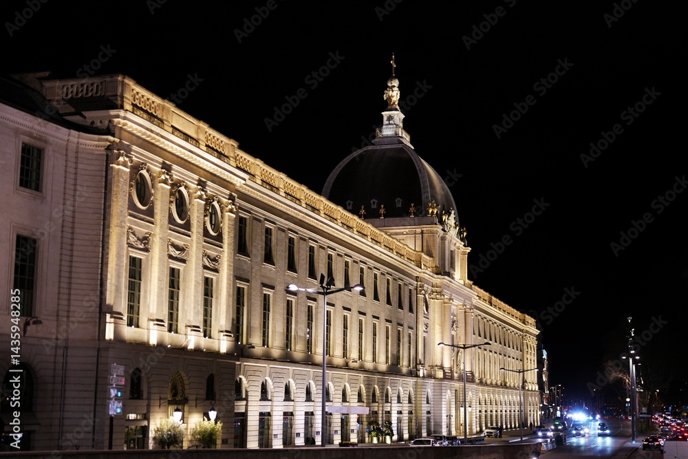 Obraz premium Grand building in Lyon France illuminated at night with busy street traffic