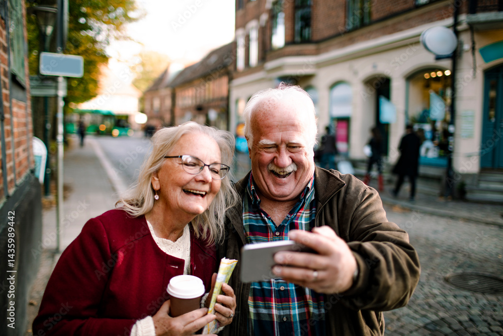 Happy senior couple taking selfie while walking in city street on vacation Happy senior couple taking selfie while walking in city street on vacation