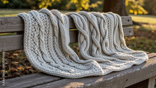 Knitted Aran sweater textures on a stone bench, dappled sunlight, cream, grey, green tones.