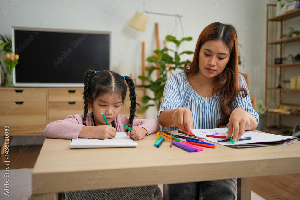Fototapeta premium Young girl and woman drawing with colorful markers at table in cozy room with plants and shelves
