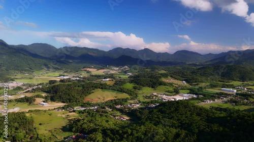 Charming countryside town nestled in lush mountains. Greenery surrounds quaint houses. Peaceful aerial view.