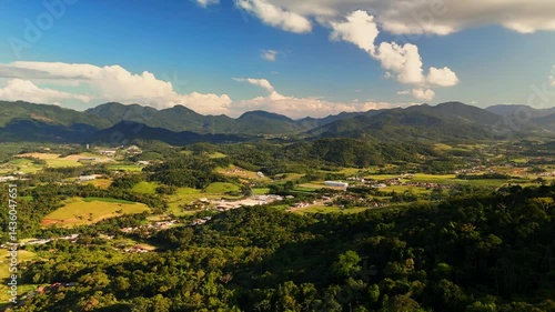 Charming countryside town nestled in lush mountains. Greenery surrounds quaint houses. Peaceful aerial view.