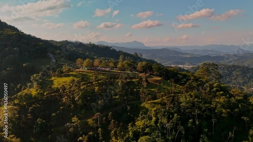 Charming countryside town nestled in lush mountains. Greenery surrounds quaint houses. Peaceful aerial view.