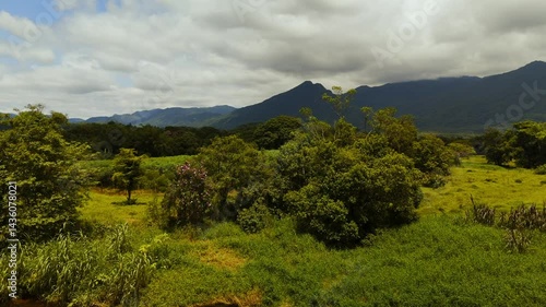 Serene river winding through green mountain valleys. Lush vegetation blankets the landscape. Peaceful flight over nature's beauty
