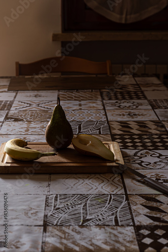 Obraz na płótnie Preparing healthy fruit: Pear, banana, cut pear on wood board, knife ready. Dramatic lighting. w salonie