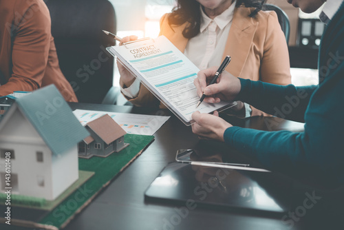 Obraz na płótnie Business team signing investment agreement for residential real estate. Group of professionals in suits meeting in office with financial agreement documents on table. w salonie