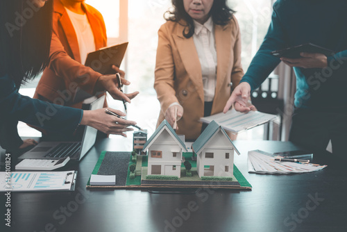 Obraz na płótnie Business team signing investment agreement for residential real estate. Group of professionals in suits meeting in office with financial agreement documents on table. w salonie