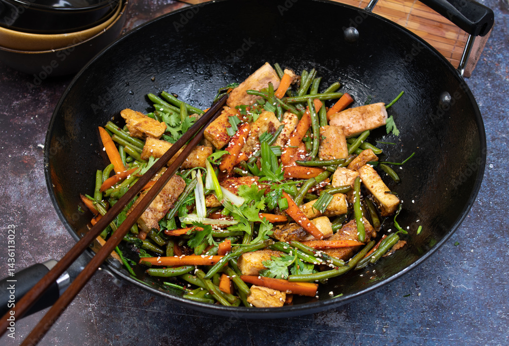 Vegan tofu, beans andcarrot stir fry in black wok, chopsticks Vegan tofu, beans andcarrot stir fry in black wok, chopsticks