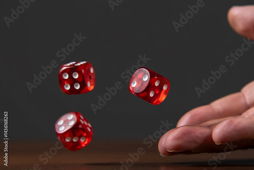 A hand rolling three red dice with red dots on a dark surface, symbolizing luck, chance, and gaming dynamics.