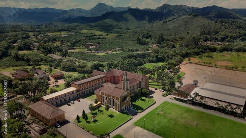 Drone captures a historic church and convent nestled amidst lush tropical mountains.