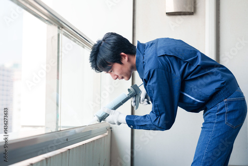 Fototapeta 外装工事でコーキング材を塗る作業員の男性