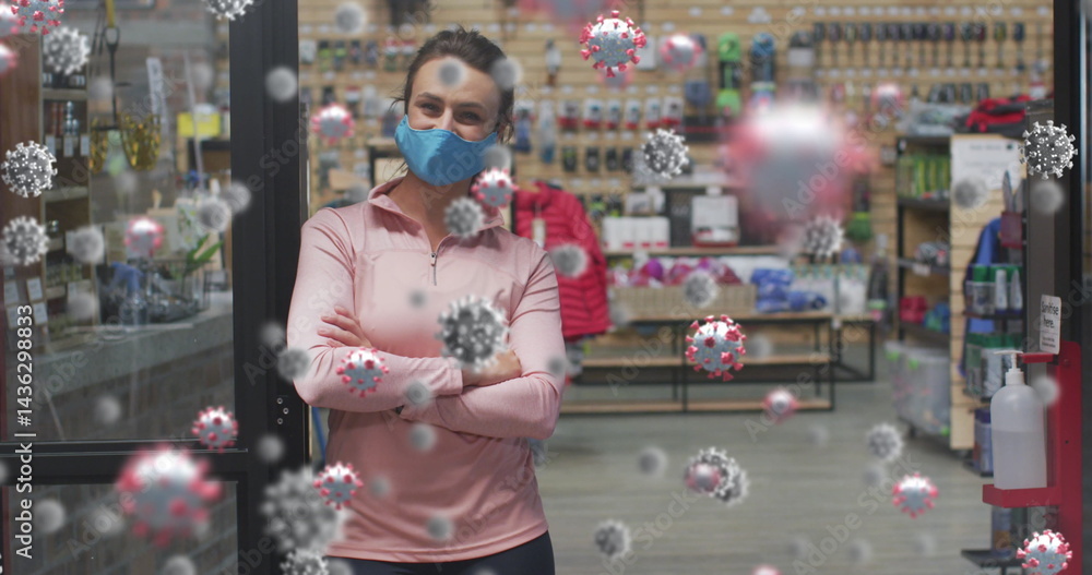 Obraz premium woman wearing blue mask, leaning against glass door inside sports shop, with sanitizer dispenser