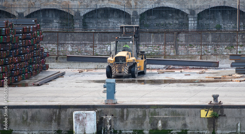 forklift handling steel beams in the port
