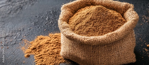Obraz na płótnie Aromatic ground cinnamon powder overflowing from rustic burlap sack on dark slate surface w salonie