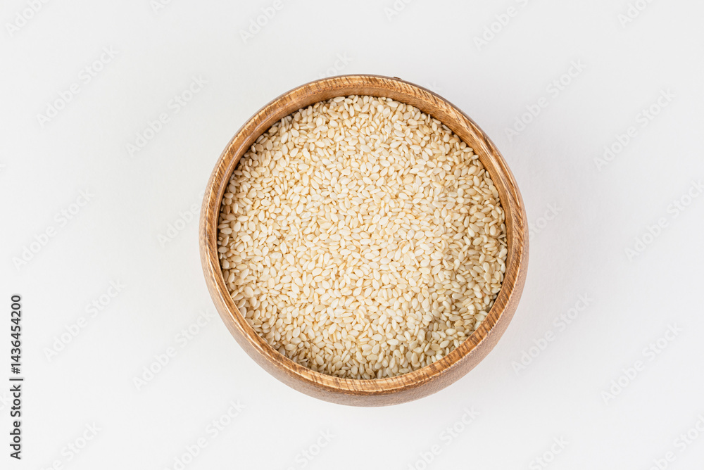 Top view of white sesame seeds in wooden bowl on white background isolated Top view of white sesame seeds in wooden bowl on white background isolated