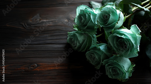 Mint green roses arranged on rich dark wooden surface