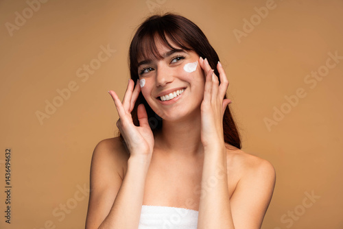 Beautiful young woman applying face luxury sunscreen or moisturizer cream for perfect hydrated healthy fresh skin care - Cosmetic dermatology product concept