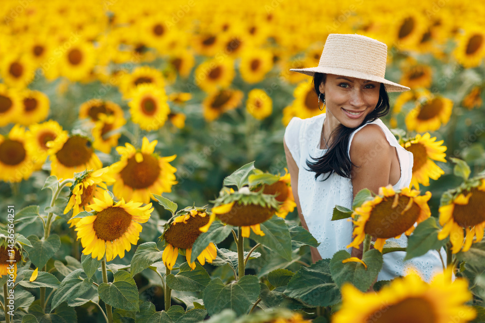 Beautiful young woman in hat on sunflower field.
