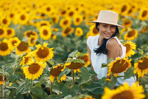 Obraz na płótnie Beautiful young woman in hat on sunflower field. w salonie