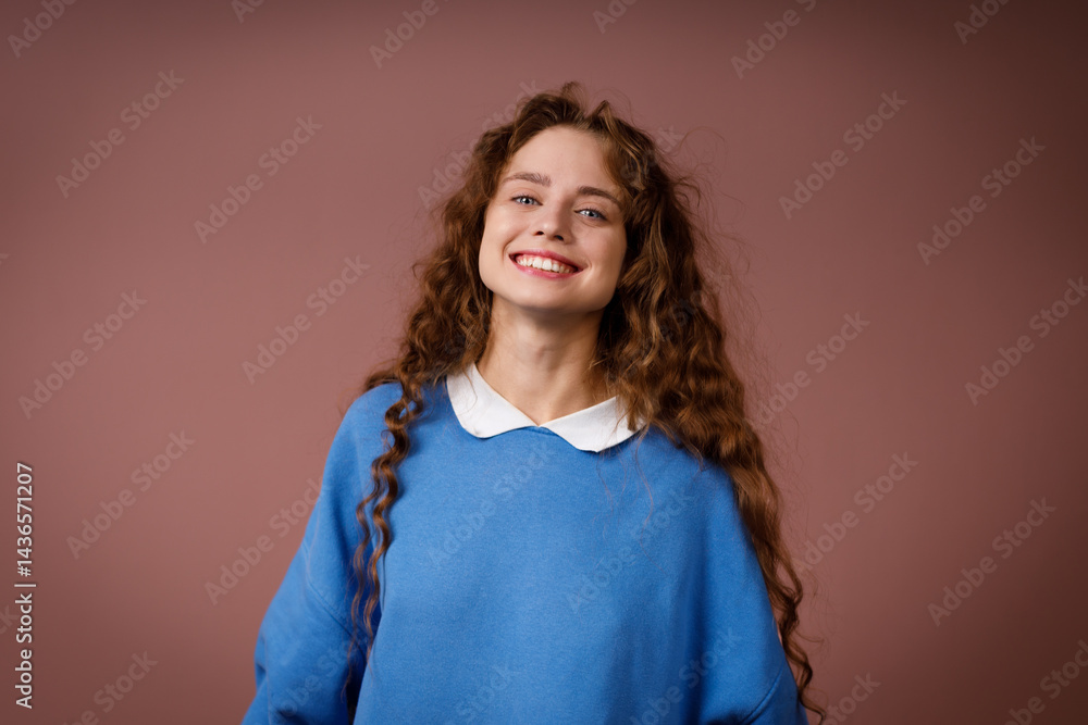 Happy young adult woman wearing winter blue sweater indoors looking at camera with joyful smile