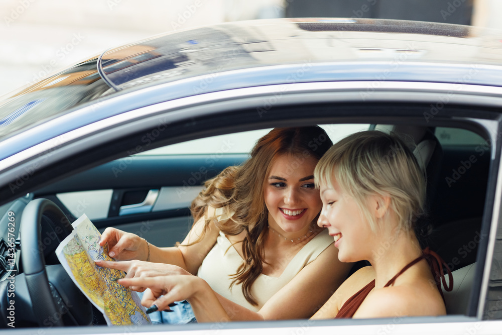 Happy young two women tourist travelers with paper map at rental car vehicle is exploring new city