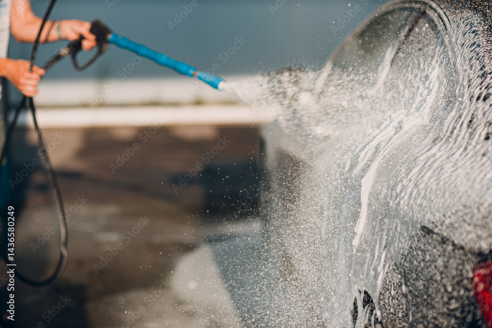 Worker washing car at self-service car wash