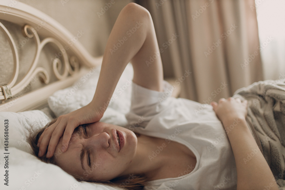 Young woman suffering with headache flu ill sick disease cold at home indoor lying on bed top view Young woman suffering with headache flu ill sick disease cold at home indoor lying on bed top view