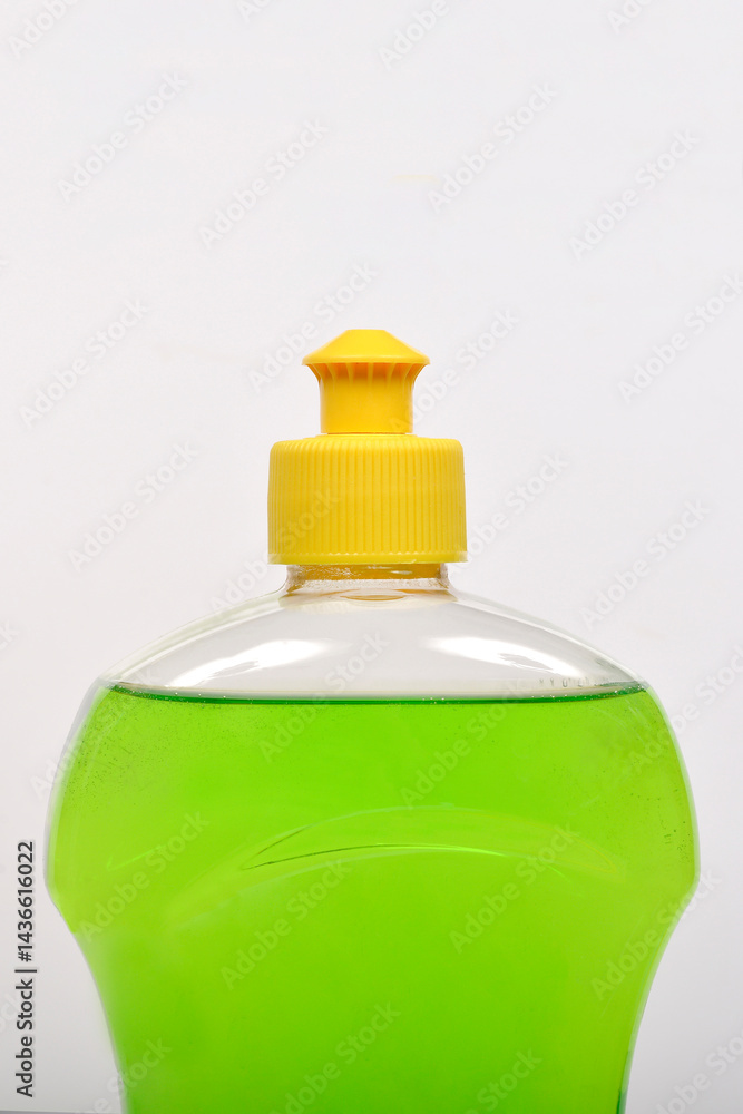 A close-up shot shows a clear plastic bottle filled with bright green dish soap and capped with a yellow lid