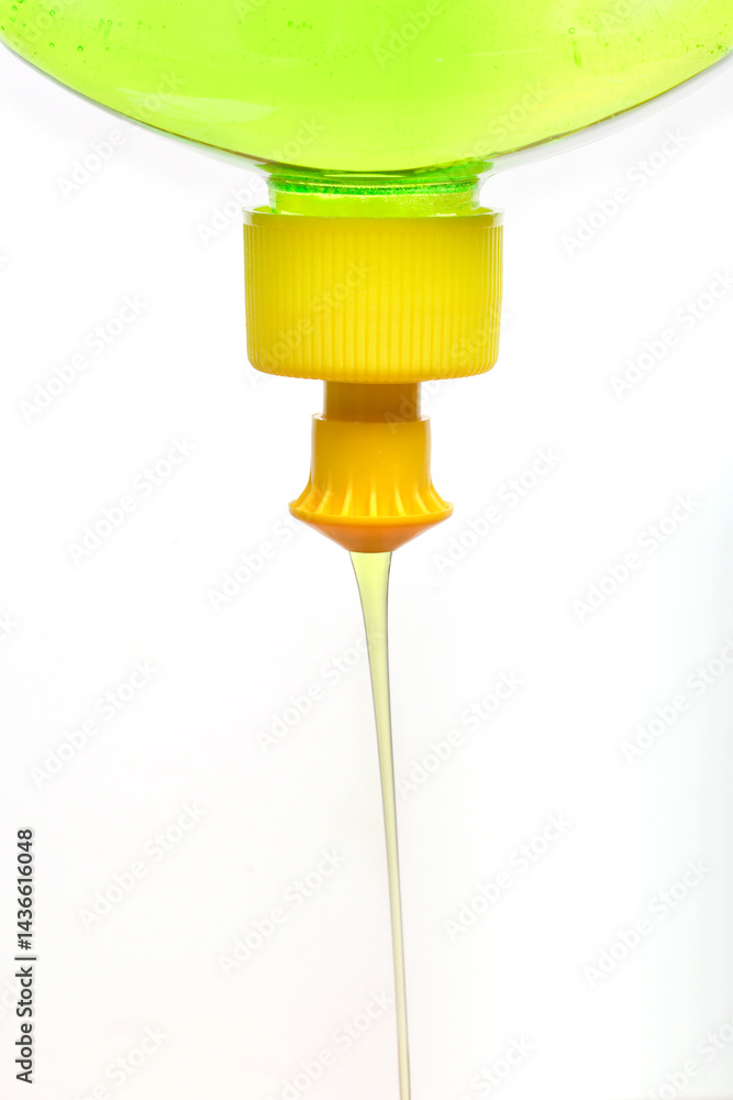 A close-up shows light green dish soap being squeezed from a yellow nozzle of a clear bottle