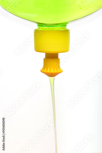 Obraz na płótnie A close-up shows light green dish soap being squeezed from a yellow nozzle of a clear bottle w salonie