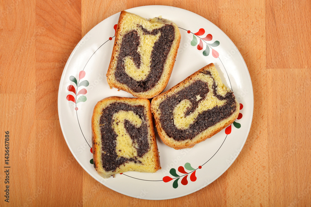 Three slices of poppy seed roll are arranged on a decorative plate