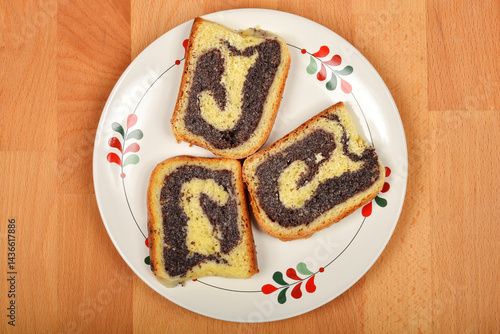 Obraz na płótnie Three slices of poppy seed roll are arranged on a decorative plate w salonie