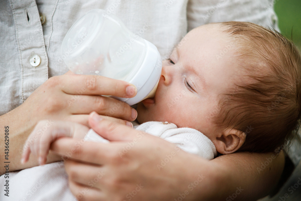 Mother feeding cute newborn baby with bottle close up in the garden. Love, care and family in countryside concept. Happy Mothers day! Adoption and maternity Mother feeding cute newborn baby with bottle close up in the garden. Love, care and family in countryside concept. Happy Mothers day! Adoption and maternity