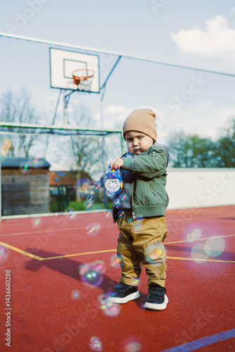 Obraz na płótnie Toddler boy running outside with soap bubbles. Child on a warm spring day for a walk in a jacket and hat. w salonie