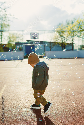 Obraz na płótnie Little cute boy 2 years old running with soap bubbles. Boy catching soap bubbles in the park, enjoying a sunny summer day. Creative activities for children outdoors w salonie