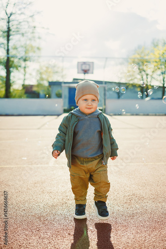 Little cute boy 2 years old running with soap bubbles. Boy catching soap bubbles in the park, enjoying a sunny summer day. Creative activities for children outdoors