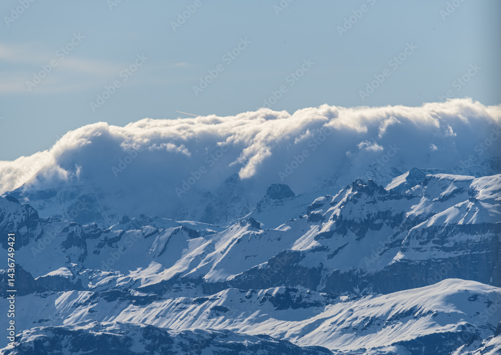 Obraz premium Majestic snow-capped mountains under a cloud-covered sky in a serene landscape during midday