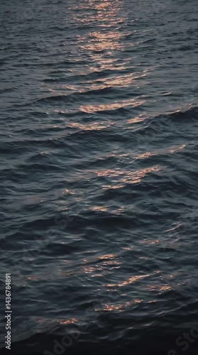 A tranquil close-up of water reflecting the golden glow of a sunset, with gentle ripples creating a shimmering effect. Perfect for nature and serenity-themed projects.