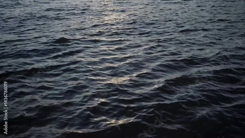 A tranquil close-up of water reflecting the golden glow of a sunset, with gentle ripples creating a shimmering effect. Perfect for nature and serenity-themed projects.