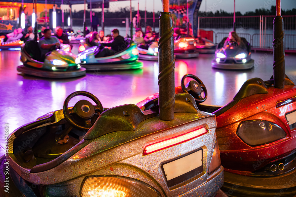 Colorful bumper car ride at a funfair during sunset with neon lights. Blurred background