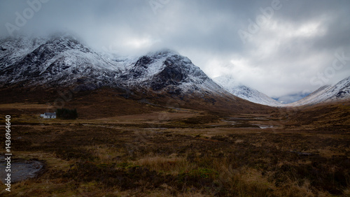 A breathtaking panoramic view of the Scottish Highlands, featuring snow-capped mountains rising above vast open moorland and rugged terrain.