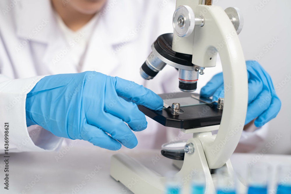 A scientist in blue gloves examines a specimen under a microscope, highlighting the importance of laboratory research and scientific exploration. A scientist in blue gloves examines a specimen under a microscope, highlighting the importance of laboratory research and scientific exploration.