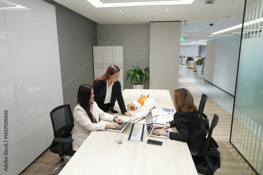 A group of male and female Asian legal co-workers use sticky notes on the wall to brainstorm and find solutions to problems in an office conference room.