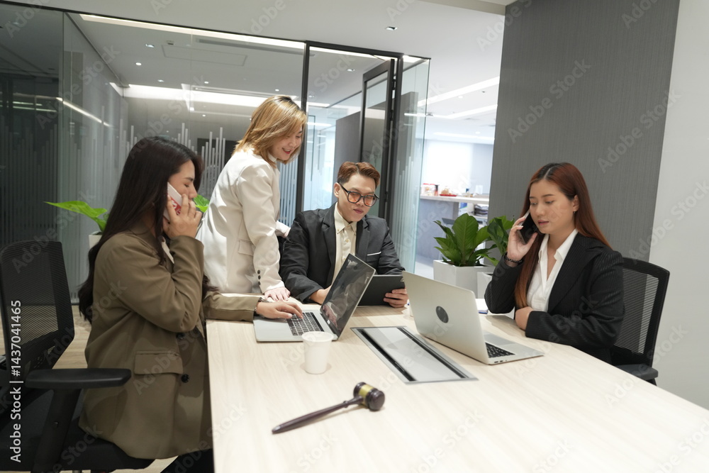 A group of male and female Asian legal co-workers use sticky notes on the wall to brainstorm and find solutions to problems in an office conference room.