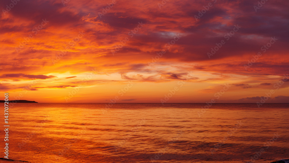 Naklejka premium Fiery Orange and Red Sunset Over Calm Ocean
