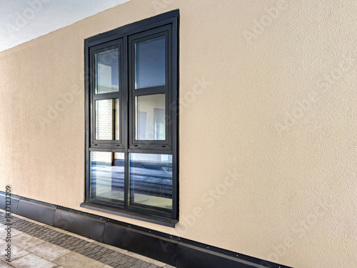 contemporary brown plastic window on beige stucco wall of an old renovated house.