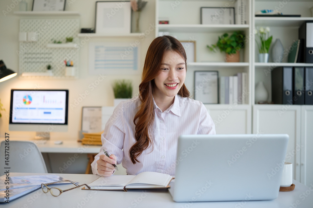 Smiling young woman working on laptop at home office, taking notes in a notebook. Smiling young woman working on laptop at home office, taking notes in a notebook.